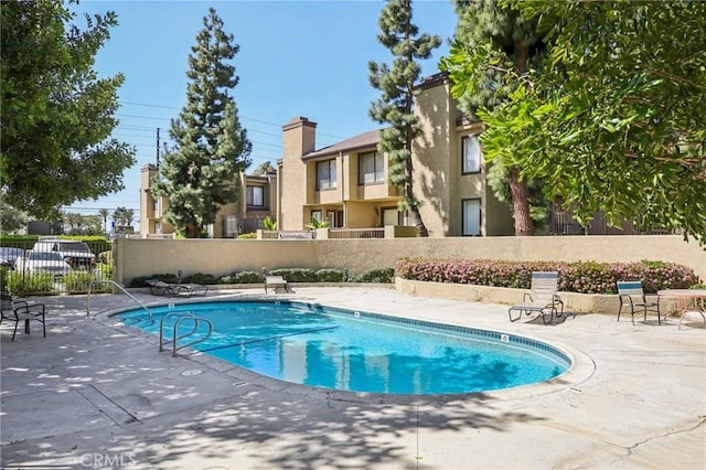 community pool featuring fence and a patio area