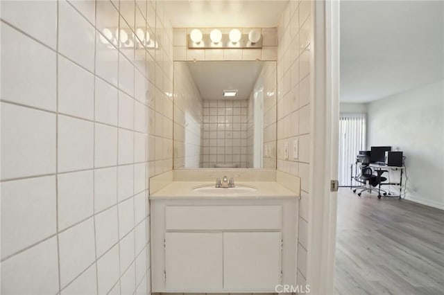 bathroom with tile walls, vanity, and wood finished floors