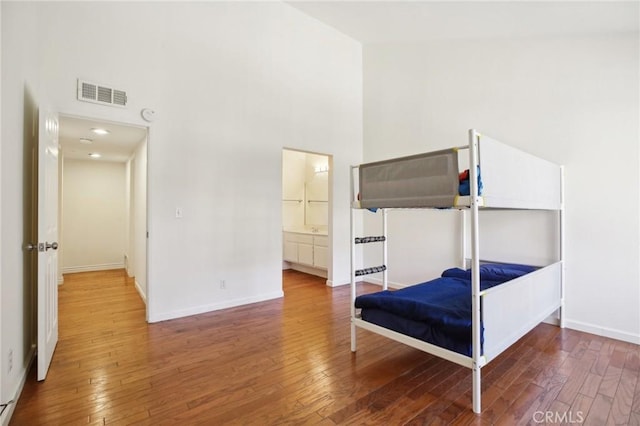 bedroom with wood-type flooring, baseboards, and a high ceiling