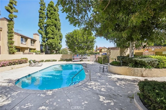 community pool with fence, a patio, and a residential view