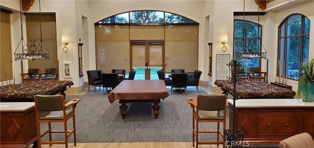 interior space featuring a towering ceiling, billiards, and french doors