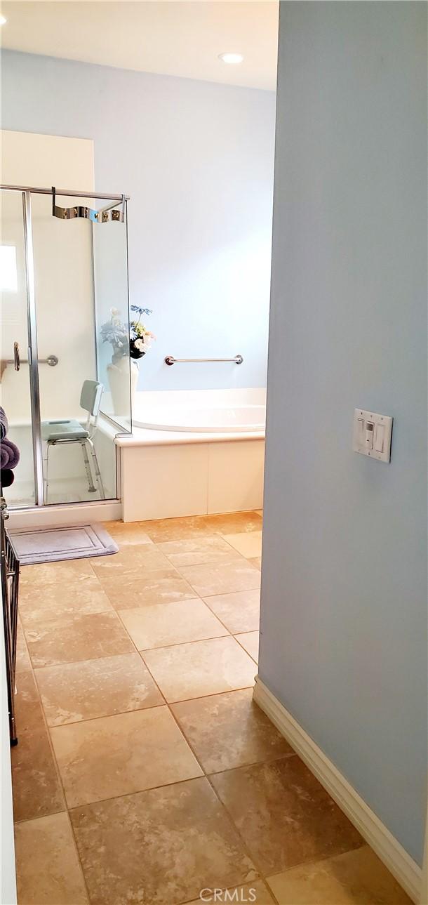 bathroom featuring baseboards, a stall shower, tile patterned flooring, and a bath