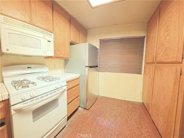 kitchen with tile counters, light wood-type flooring, and white appliances