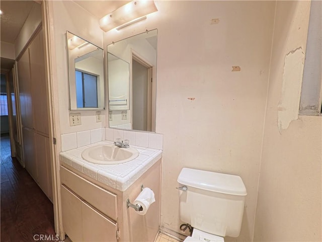 half bathroom featuring toilet, vanity, and wood finished floors