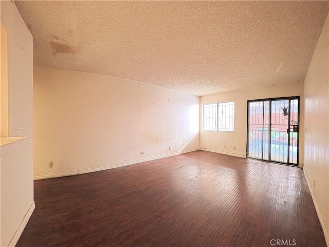empty room featuring baseboards, wood finished floors, and a textured ceiling