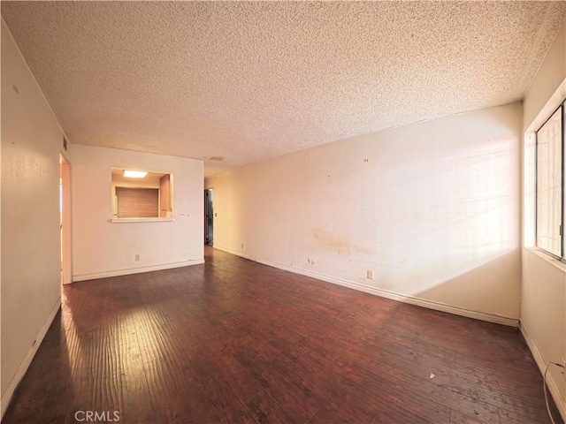 unfurnished room with hardwood / wood-style flooring, baseboards, and a textured ceiling