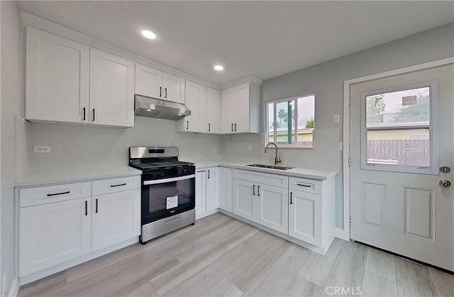 805 Earlham St, Pasadena, CA 91101 - kitchen with white cabinetry, light countertops, under cabinet range hood, stainless steel gas stove, and a sink