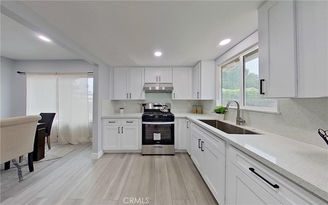805 Earlham St, Pasadena, CA 91101 - kitchen with white cabinets, under cabinet range hood, a sink, light wood-type flooring, and gas range