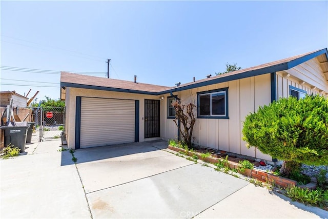 ranch-style home with board and batten siding, fence, a gate, an attached garage, and driveway