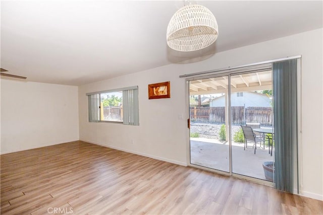 empty room featuring a chandelier, baseboards, and wood finished floors
