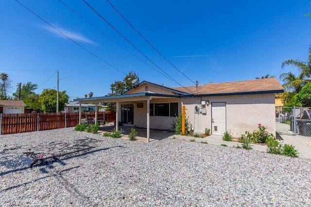 view of front of property featuring fence, a patio, and stucco siding