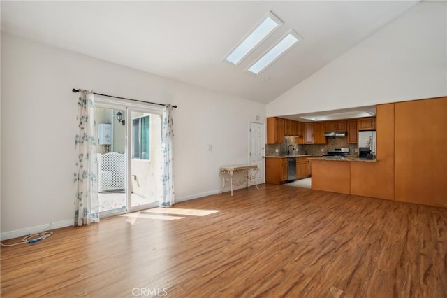 kitchen featuring a skylight, appliances with stainless steel finishes, brown cabinetry, and light wood finished floors