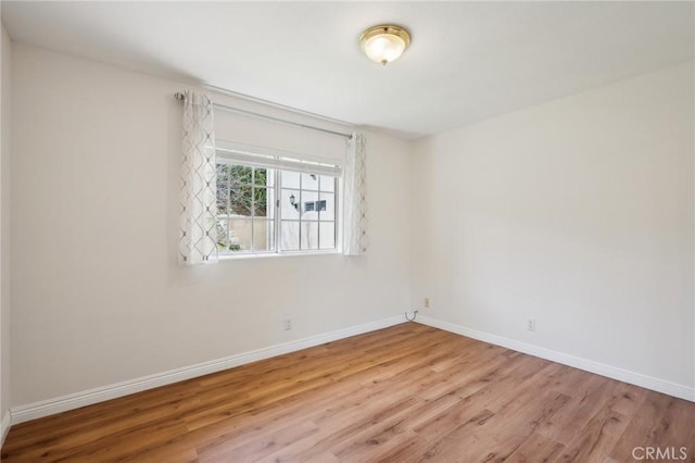 spare room featuring baseboards and wood finished floors
