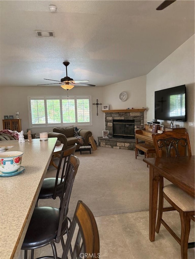 16633 Neenach Rd, Apple Valley, CA 92307 - dining area featuring a ceiling fan, a textured ceiling, light carpet, and a stone fireplace