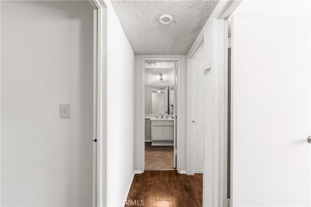 19231 Sherman Way Unit 44, Reseda, CA 91335 - hall featuring dark wood finished floors, baseboards, a sink, and a textured ceiling