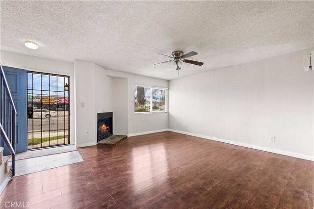 19231 Sherman Way Unit 44, Reseda, CA 91335 - unfurnished living room featuring stairs, a warm lit fireplace, wood finished floors, baseboards, and ceiling fan