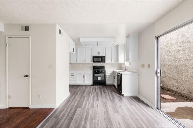 19231 Sherman Way Unit 44, Reseda, CA 91335 - kitchen featuring light wood-type flooring, white cabinets, black appliances, and visible vents