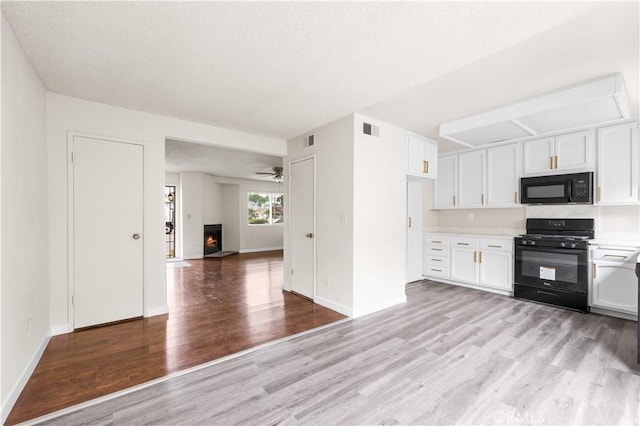 19231 Sherman Way Unit 44, Reseda, CA 91335 - kitchen with light countertops, white cabinets, light wood-style floors, open floor plan, and black appliances