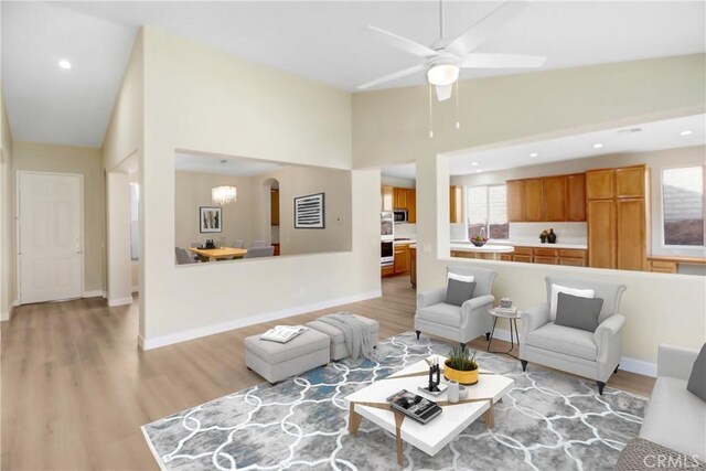 living room with ceiling fan, light wood-style floors, arched walkways, recessed lighting, and baseboards