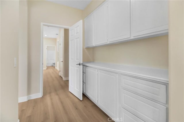 hall featuring light wood-type flooring and baseboards
