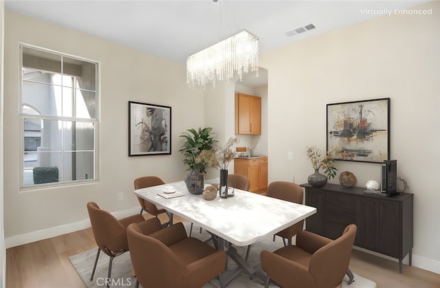 dining space with visible vents, baseboards, a notable chandelier, and light wood finished floors