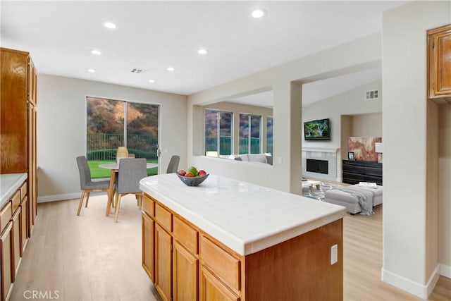 kitchen featuring tile counters, recessed lighting, light wood-type flooring, a kitchen island, and visible vents