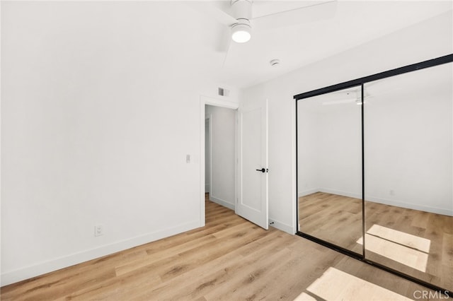 unfurnished bedroom featuring visible vents, baseboards, a closet, ceiling fan, and wood finished floors