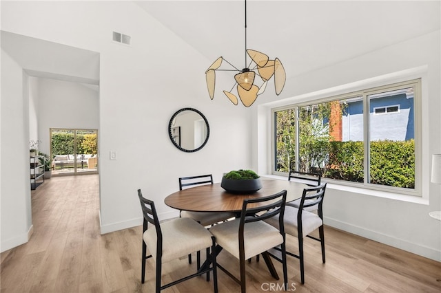 dining room with visible vents, baseboards, high vaulted ceiling, and light wood finished floors