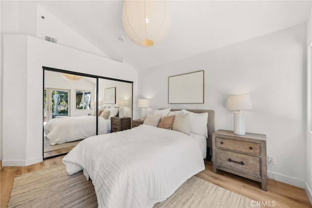 bedroom featuring visible vents, baseboards, vaulted ceiling, and wood finished floors