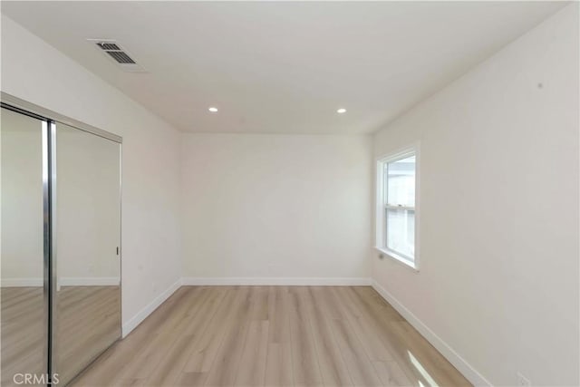 unfurnished bedroom featuring recessed lighting, baseboards, light wood finished floors, visible vents, and a closet