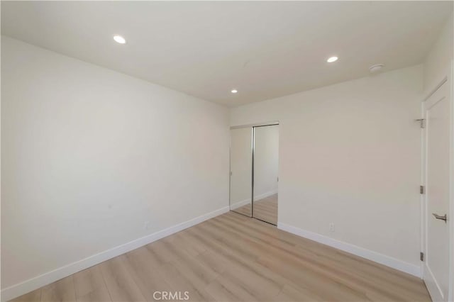 unfurnished bedroom featuring baseboards, a closet, light wood-style floors, and recessed lighting