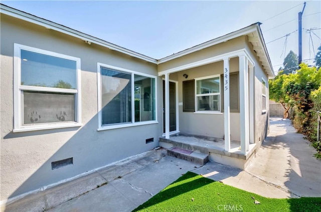 doorway to property featuring crawl space and stucco siding