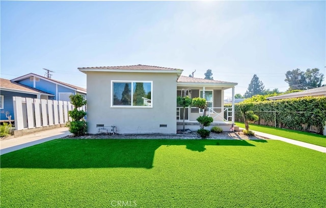 rear view of property with a sunroom, stucco siding, fence, crawl space, and a lawn