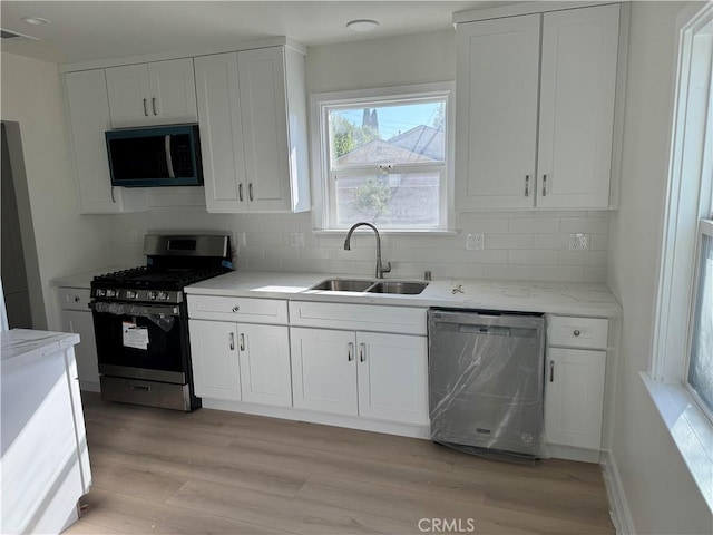 kitchen featuring light wood finished floors, a sink, white cabinets, and appliances with stainless steel finishes