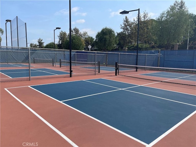 view of tennis court with community basketball court and fence