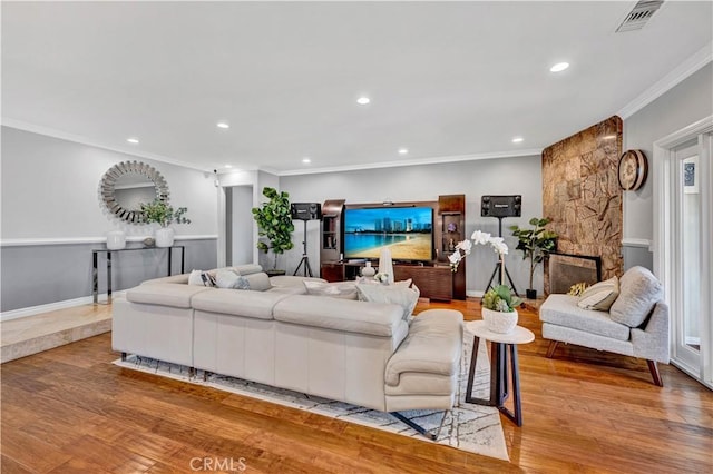 living area featuring recessed lighting, ornamental molding, visible vents, and light wood-style floors