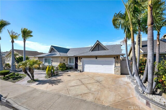 ranch-style house with stucco siding, stone siding, driveway, a gate, and a garage
