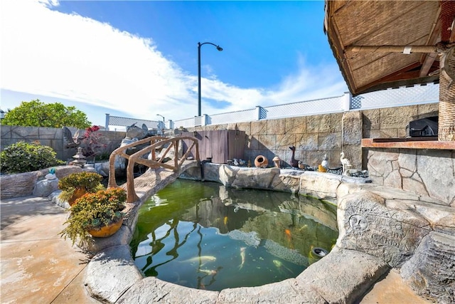 exterior space with a fenced backyard and a small pond