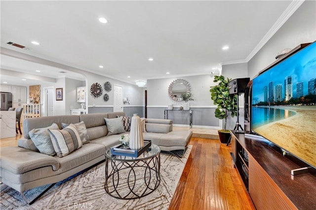 living room featuring visible vents, crown molding, light wood finished floors, recessed lighting, and arched walkways