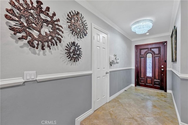 entryway with baseboards, ornamental molding, and a notable chandelier