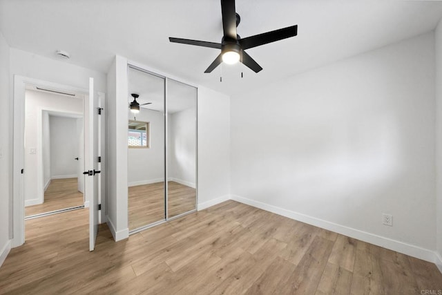 unfurnished bedroom featuring baseboards, light wood-type flooring, and a closet