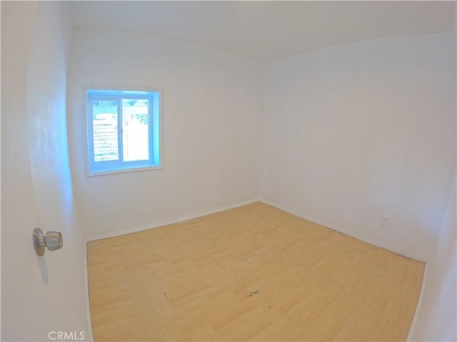 spare room with baseboards and wood finished floors