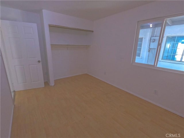 unfurnished bedroom with baseboards, light wood-style floors, and a closet