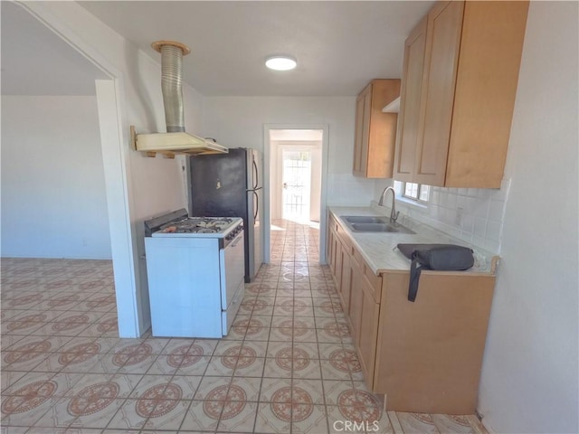kitchen featuring wall chimney range hood, white gas stove, a sink, light countertops, and backsplash