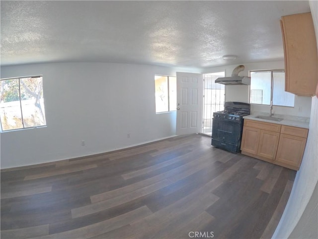 kitchen with dark wood-type flooring, a textured ceiling, black gas stove, and wall chimney range hood