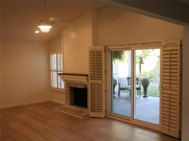 unfurnished living room with baseboards, wood finished floors, a fireplace, and high vaulted ceiling