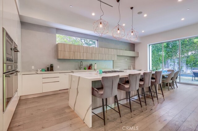 737 N Cherokee Ave, Los Angeles, CA 90038 - kitchen with light countertops, a spacious island, backsplash, light wood finished floors, and modern cabinets