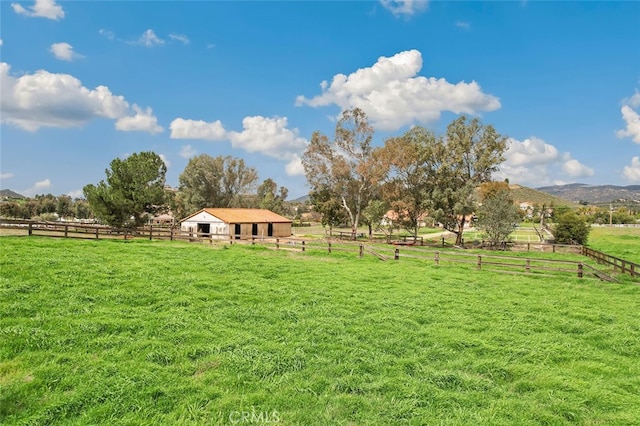 view of yard with fence, an outdoor structure, a rural view, and an exterior structure