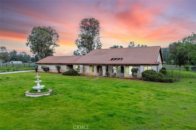 view of front facade featuring fence, a front lawn, a tiled roof, and stucco siding