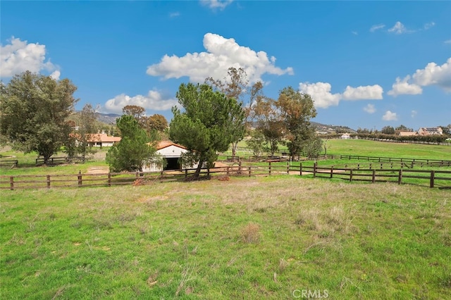 view of yard featuring an outbuilding, a mountain view, and a rural view
